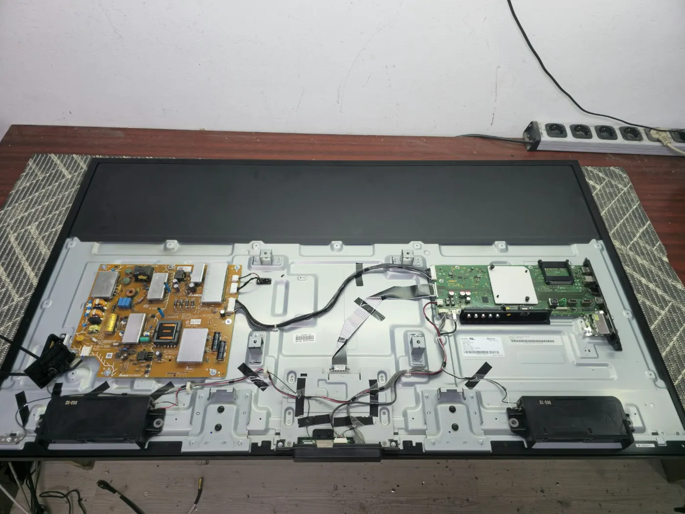 Televizor Sony KD-55XE8096 desfăcut pe bancul de lucru, cu sursa și placa de bază la vedere